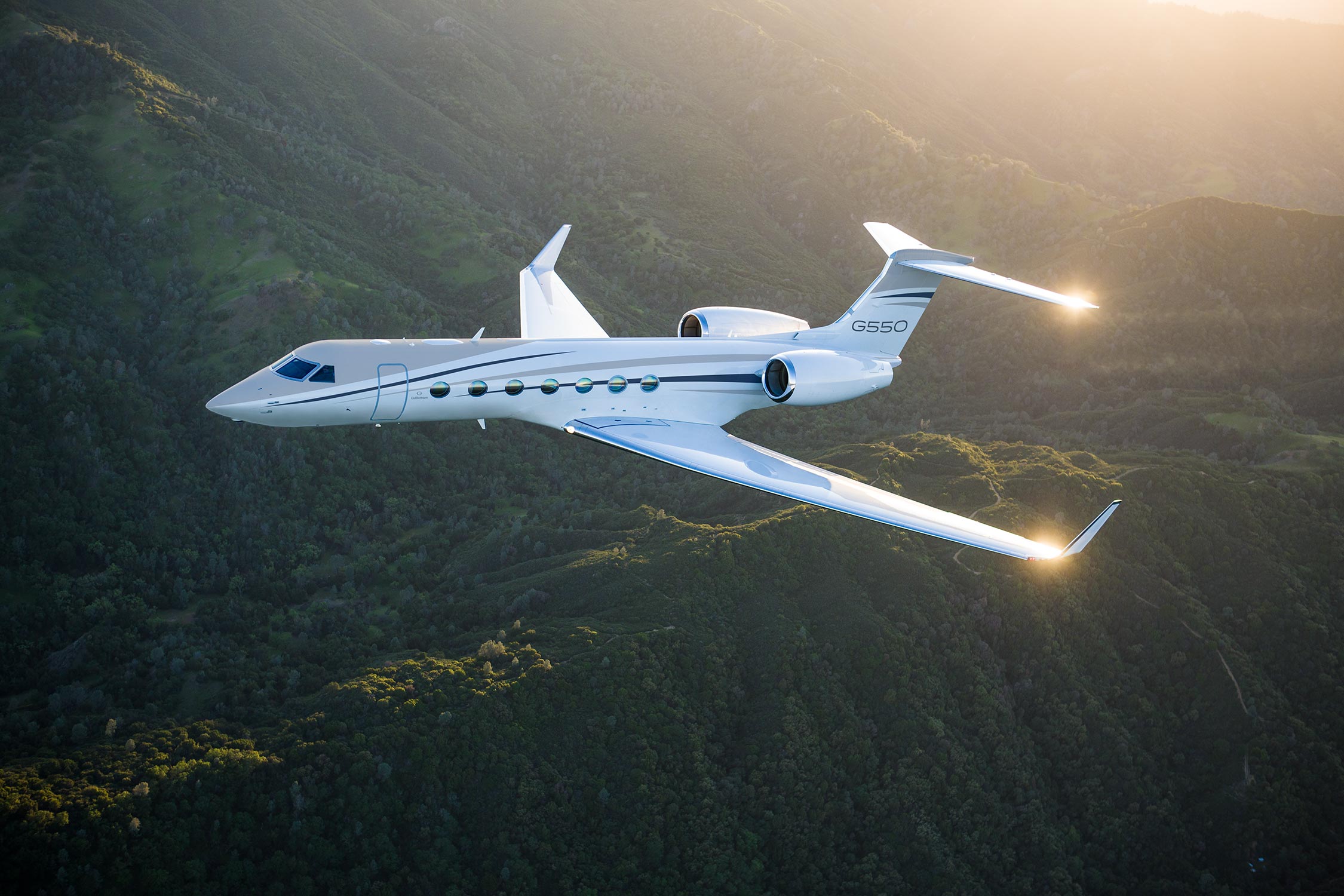 G550 flying over green mountains