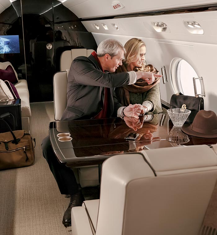 A man and woman staring out the window from their private aircraft